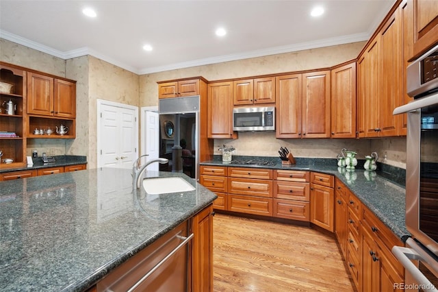 kitchen with dark stone counters, sink, ornamental molding, light hardwood / wood-style floors, and stainless steel appliances