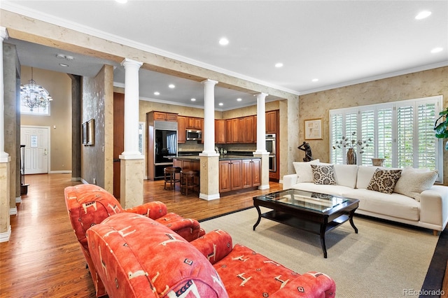 living room with light wood-type flooring, ornamental molding, and ornate columns