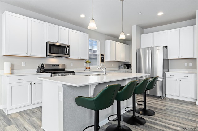 kitchen featuring white cabinets, appliances with stainless steel finishes, hanging light fixtures, and sink