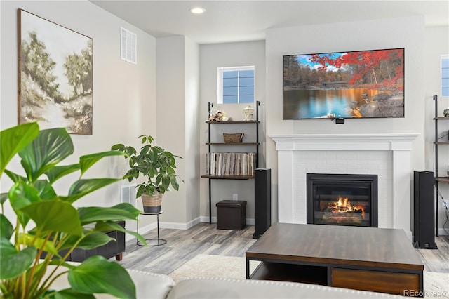 living room featuring light hardwood / wood-style floors and a brick fireplace