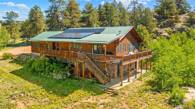 3980 County Rd 71, Guffey, CO 80820 - rear view of house featuring log exterior, roof mounted solar panels, stairway, a metal roof, and a porch