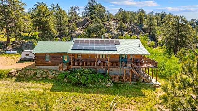 3980 County Rd 71, Guffey, CO 80820 - rear view of property with stairway, log exterior, roof mounted solar panels, and a metal roof