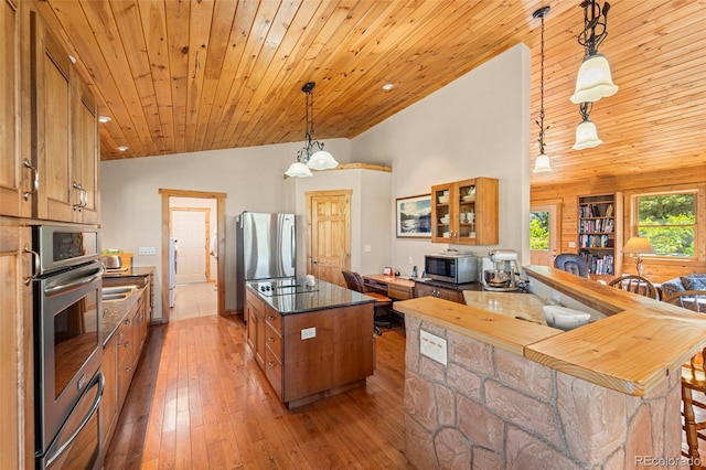 3980 County Rd 71, Guffey, CO 80820 - kitchen with vaulted ceiling, appliances with stainless steel finishes, brown cabinetry, wood ceiling, and glass insert cabinets