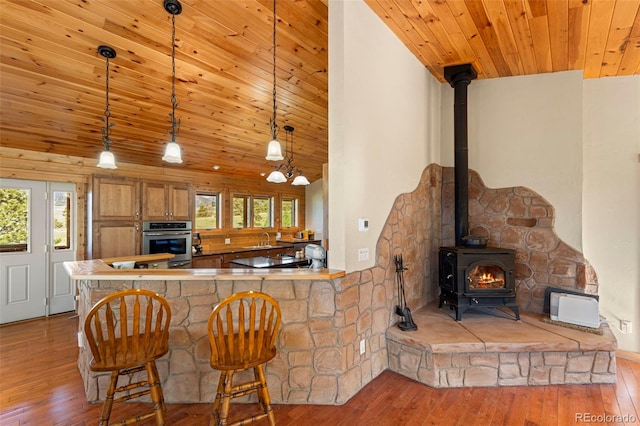 3980 County Rd 71, Guffey, CO 80820 - kitchen with oven, a wood stove, hardwood / wood-style floors, wooden ceiling, and brown cabinets