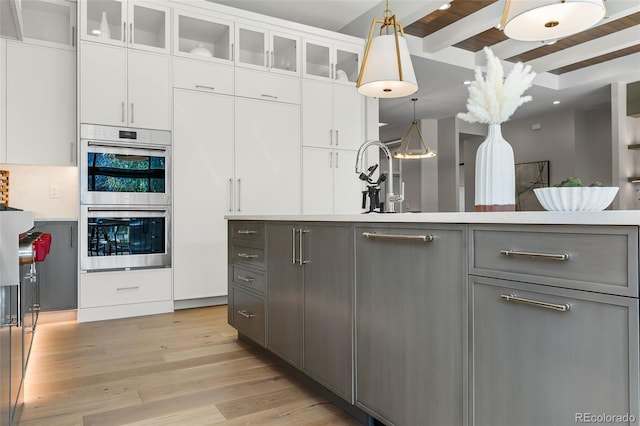 kitchen featuring beamed ceiling, white cabinets, gray cabinetry, and double oven