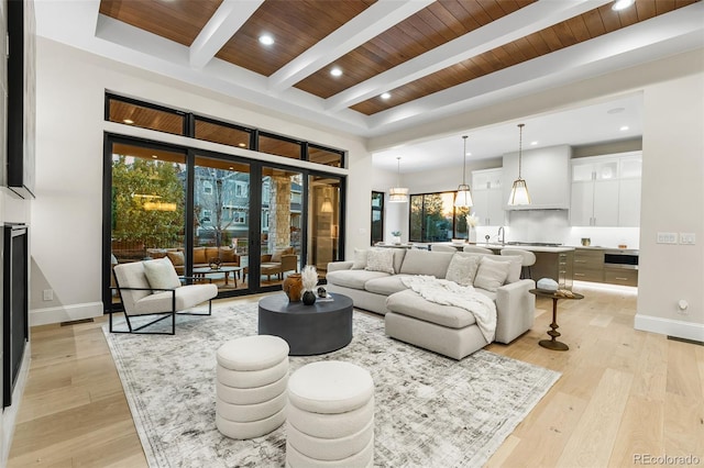 living room with beamed ceiling, wood ceiling, a high ceiling, and light hardwood / wood-style flooring