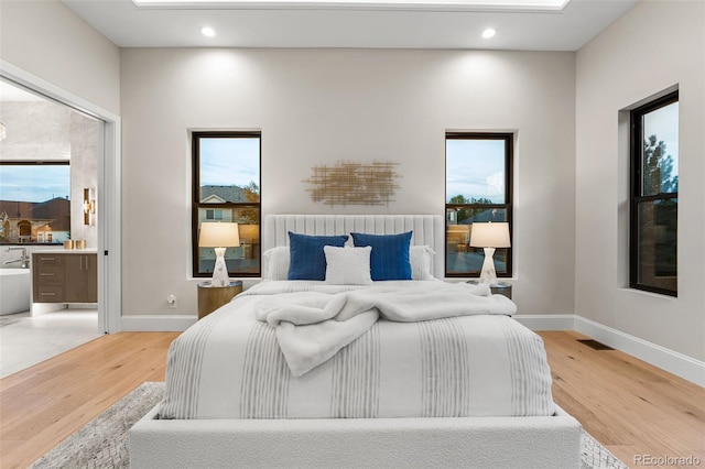 bedroom with wood-type flooring and ensuite bath