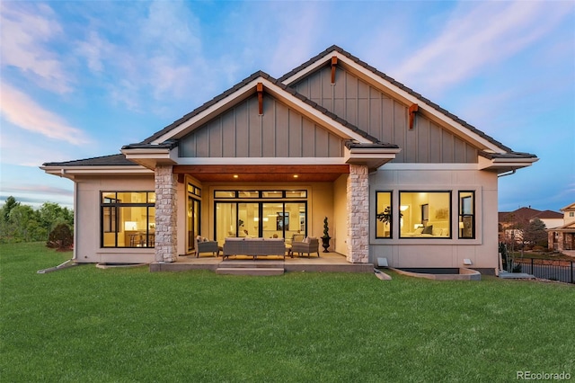 rear view of property featuring a lawn, an outdoor living space, and a patio