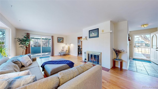 living area featuring a fireplace with flush hearth, light wood-style flooring, and baseboards