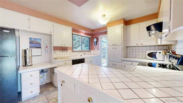 kitchen with tile countertops, white cabinets, ventilation hood, decorative backsplash, and black appliances