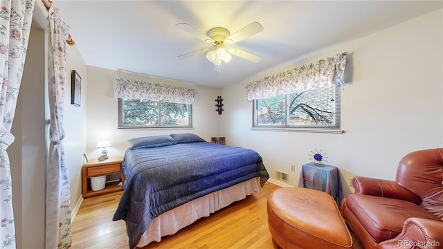 bedroom with ceiling fan, light wood-type flooring, visible vents, and baseboards