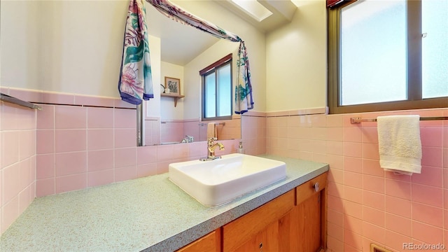 bathroom with a wainscoted wall, tile walls, and vanity