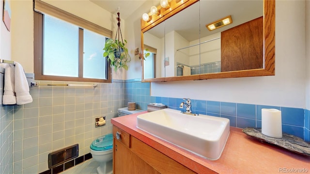 full bath featuring tile walls, visible vents, toilet, vanity, and walk in shower