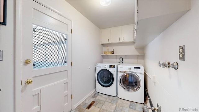 clothes washing area with cabinet space, stone finish flooring, baseboards, and washing machine and clothes dryer