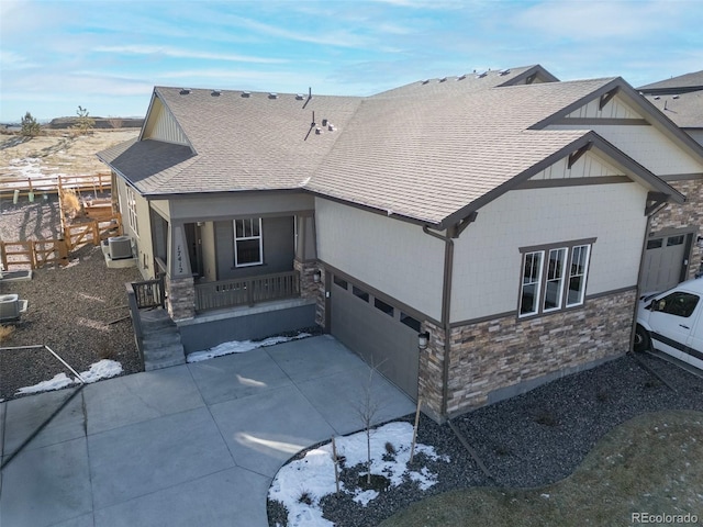 view of front of home with a garage, covered porch, and central AC unit