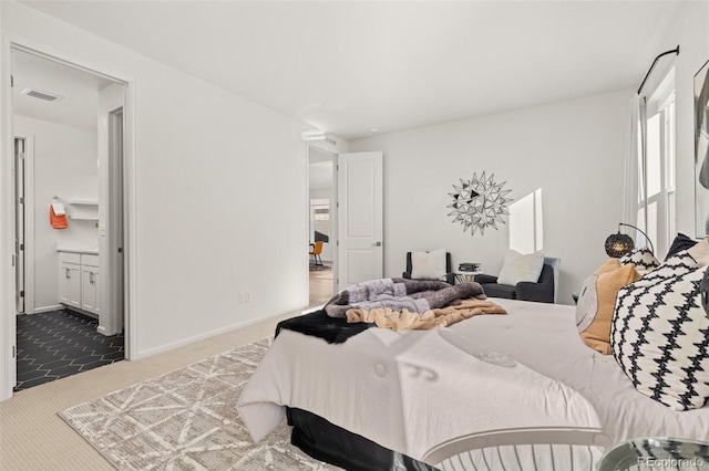 bedroom with ensuite bathroom and light carpet