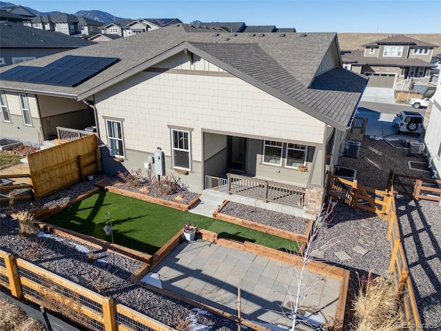 rear view of property featuring central air condition unit and solar panels