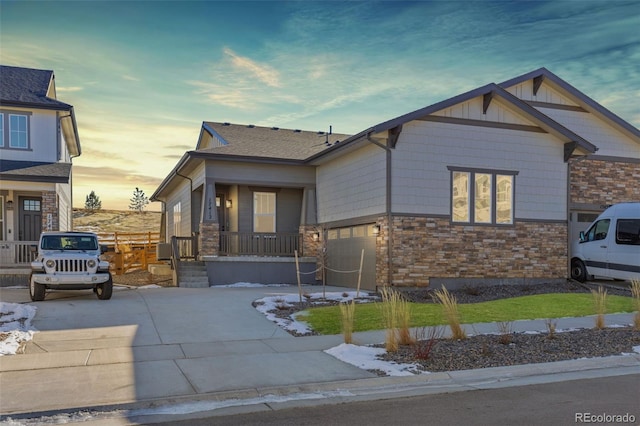 view of front of home with a front yard, stone siding, and concrete driveway