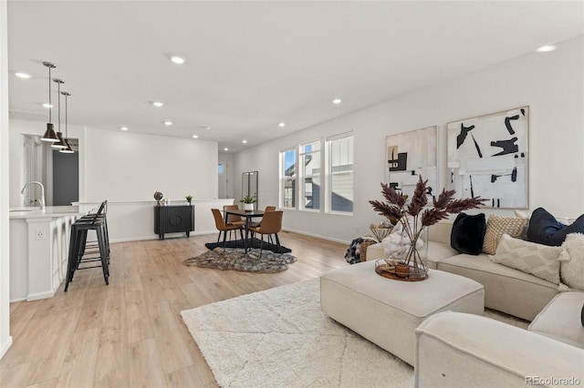 living area featuring baseboards, light wood-type flooring, and recessed lighting