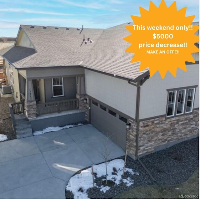 17412 W 93rd Pl, Arvada, CO 80007 - view of front of property with covered porch, stone siding, driveway, and a shingled roof