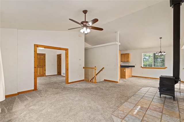 unfurnished living room featuring light colored carpet, lofted ceiling, ceiling fan, baseboards, and a wood stove
