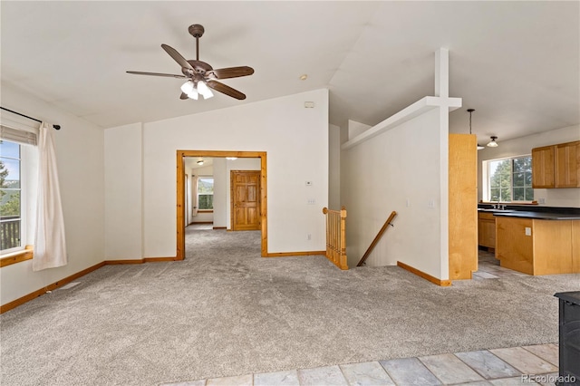 unfurnished living room featuring lofted ceiling, light carpet, baseboards, and ceiling fan