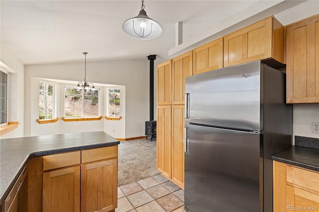 kitchen featuring freestanding refrigerator, a wood stove, vaulted ceiling, dark countertops, and decorative light fixtures