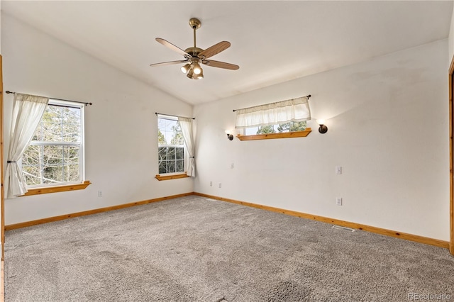 carpeted spare room featuring healthy amount of natural light, baseboards, a ceiling fan, and vaulted ceiling