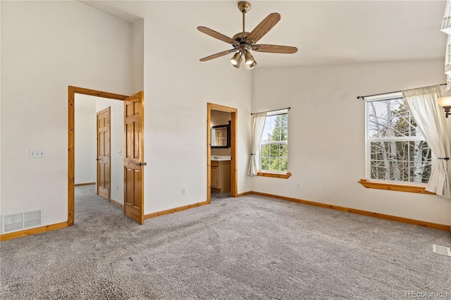 carpeted empty room featuring baseboards, ceiling fan, and high vaulted ceiling