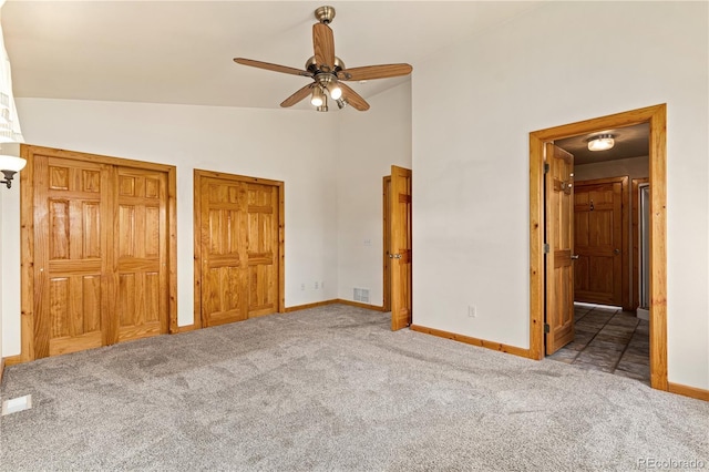 unfurnished bedroom with carpet floors, lofted ceiling, baseboards, multiple closets, and ensuite bathroom