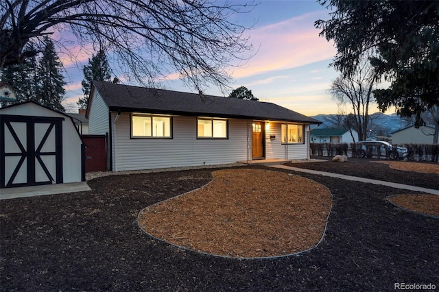 view of front of property featuring a storage shed, fence, and an outdoor structure