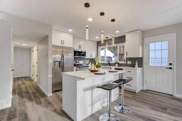 kitchen with decorative backsplash, light countertops, white cabinets, and stainless steel appliances