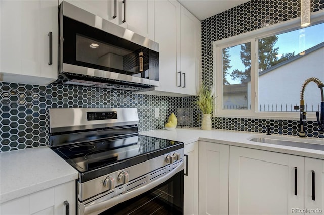 kitchen featuring white cabinets, tasteful backsplash, appliances with stainless steel finishes, and a sink