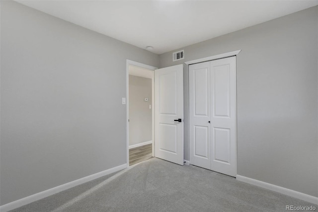 unfurnished bedroom with light colored carpet, visible vents, a closet, and baseboards