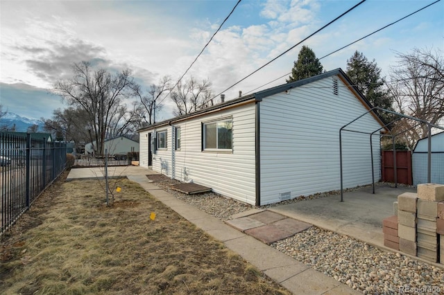 view of side of home featuring a storage shed, a patio area, a fenced backyard, and an outbuilding