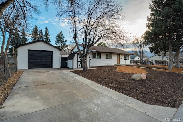 ranch-style home with fence, concrete driveway, stucco siding, a garage, and an outdoor structure