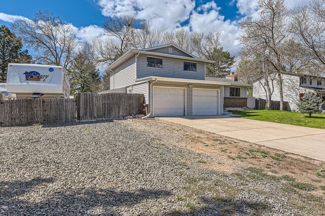 view of side of home featuring a chimney, a lawn, a garage, fence, and concrete driveway