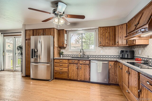 kitchen featuring light wood finished floors, tasteful backsplash, brown cabinets, and stainless steel appliances