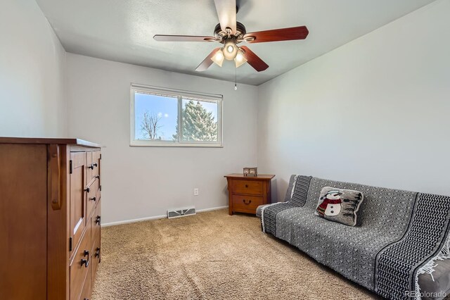 sitting room featuring a ceiling fan, baseboards, visible vents, and carpet