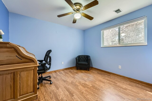 home office with light wood-style floors, baseboards, a ceiling fan, and visible vents