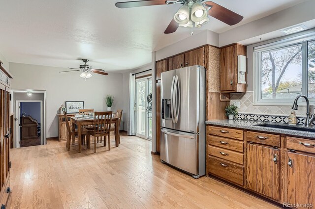 kitchen featuring brown cabinets, a ceiling fan, stainless steel fridge, and a sink