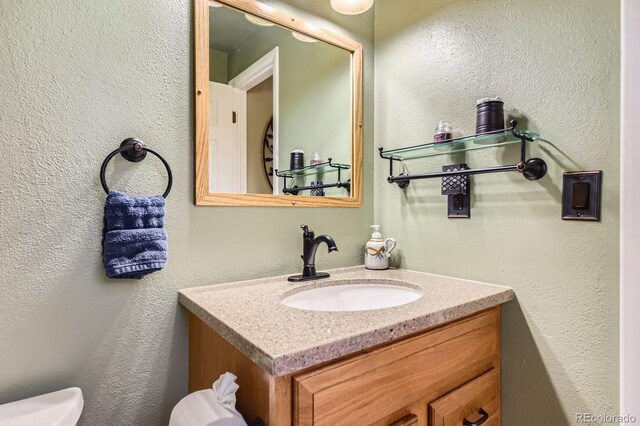 bathroom with vanity, a textured wall, and toilet