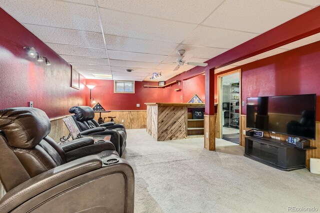 living room featuring carpet flooring, wainscoting, a dry bar, wood walls, and a paneled ceiling