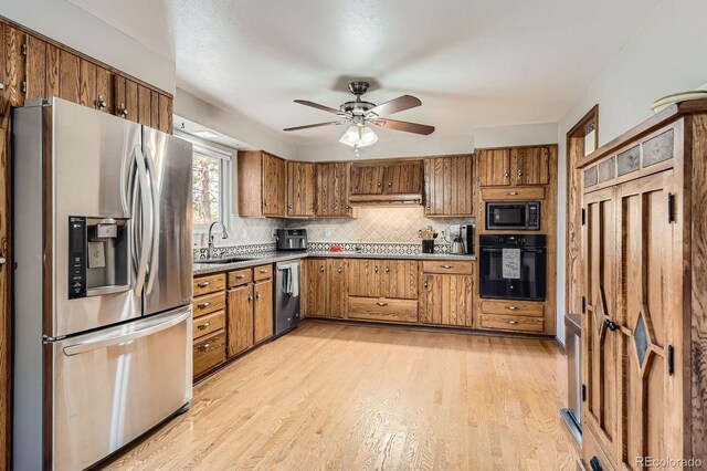 kitchen with a sink, brown cabinetry, and black appliances