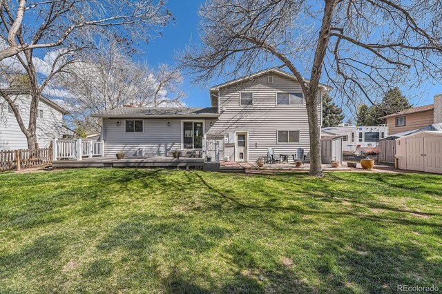 back of house featuring a deck, an outbuilding, fence, a shed, and a yard