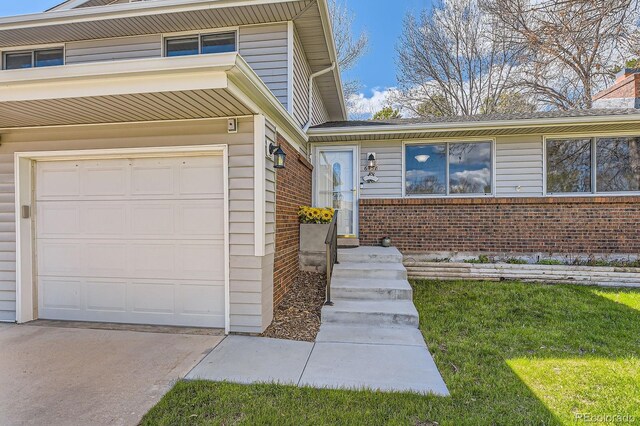 doorway to property featuring brick siding, an attached garage, driveway, and a chimney