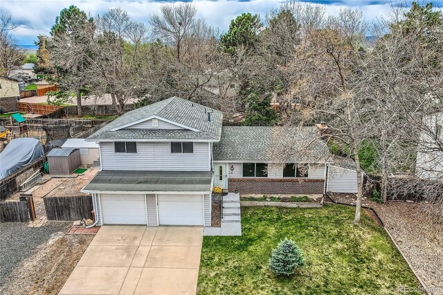 tri-level home featuring fence, a shingled roof, a front lawn, a garage, and concrete driveway