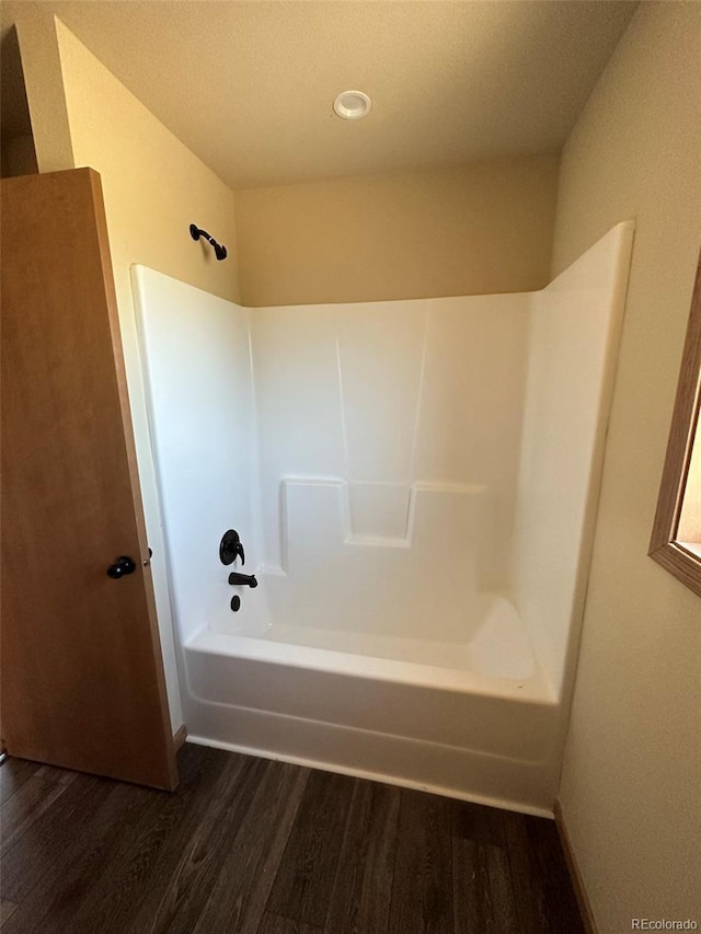 bathroom with hardwood / wood-style flooring and bathing tub / shower combination