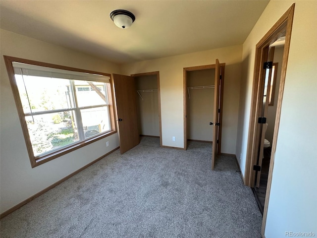 unfurnished bedroom featuring carpet floors and multiple closets