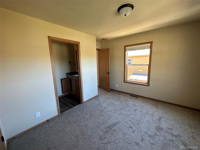 unfurnished bedroom with dark colored carpet and connected bathroom